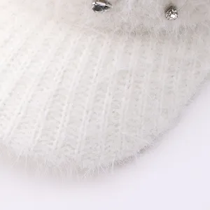 Vue détaillée du bonnet d'hiver en tricot blanc avec une texture pelucheuse et des strass brillants.