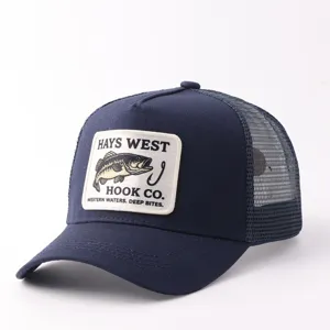 Detalle de gorra trucker de malla azul marino con parche bordado de pez y parte trasera transpirable.