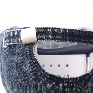 Detailopname van de achterste band van een denim baseballpet met verstelbare metalen gesp.