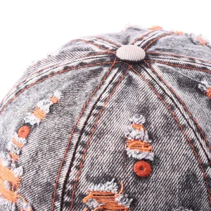 Detailed view of the top crown of a vintage distressed denim baseball cap with orange accents.