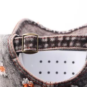Close-up of distressed denim baseball cap back strap with metal buckle and detailed stitching.