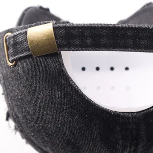 Detail view of black distressed denim baseball cap with adjustable metal buckle and inner shaper.