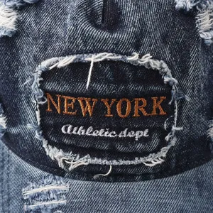 Vintage versleten denim honkbalpet detailopname met patch en gerafelde stoftekstuur.