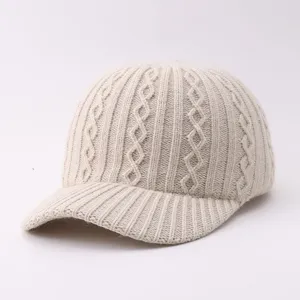 Beige cable knit baseball hat detail showing soft warm woolen texture and classic brim design.