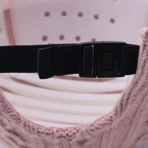 Adjustable strap detail of pink knitted baseball cap, elastic band with plastic buckle close-up.