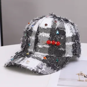 Zwart-witte tweed honkbalpet met kleurrijke strass-steentjes en decoratieve rode parelbroche.