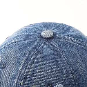 Close up of denim baseball cap top detail, showing dark blue fabric texture and center button.