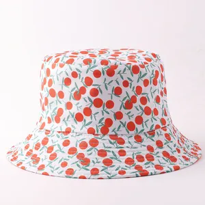 Detalle del elegante sombrero de pescador con estampado de frutas rojas y hojas verdes.
