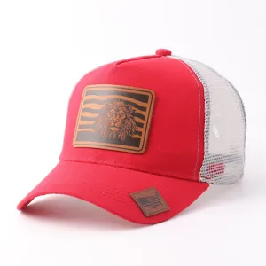 Vista detallada de la gorra trucker de malla roja y blanca con parche de cuero de león.