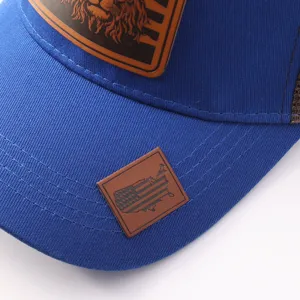 Primer plano detallado de gorra trucker azul con parche de cuero de león y mapa de bandera.