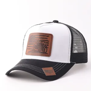 Vista detallada de la gorra trucker negra y blanca con un parche de cuero marrón distintivo.