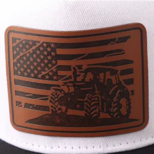 Primer plano detallado de gorra blanca con parche de cuero grabado bandera y tractor.
