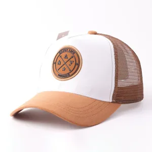 Detailopname van de bruine suède en witte mesh truckerhat met het patchontwerp aan de voorkant.