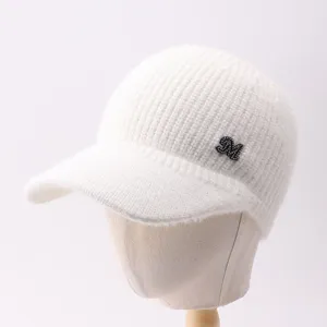 Detalle gorra béisbol punto blanca, gorro invierno cálido con logo letra M de brillantes.