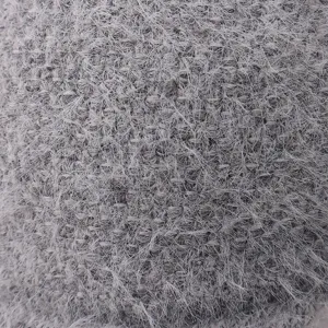 Primer plano del tejido de gorro de invierno de punto gris esponjoso, textura suave y cálida.