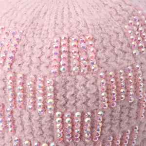 Gros plan detail d un bonnet d hiver rose en tricot avec des strass brillants et irises.