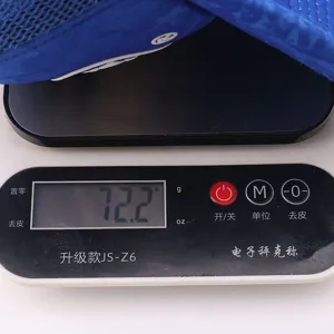 Detail view of a blue mesh trucker hat on a digital scale, showing lightweight design and quality.