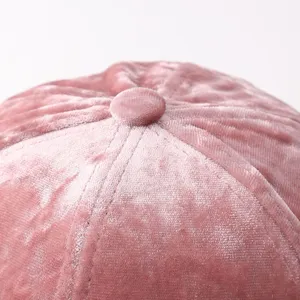 Primo piano sul bottone superiore e sulle cuciture di un berretto in velluto rosa.