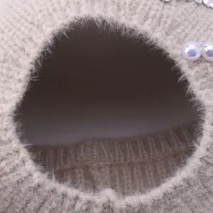Close-up detail of winter warm knitted plush hat with elegant pearls and sparkling rhinestones.
