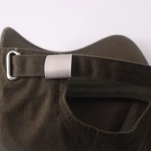 Primer plano detallado de la hebilla de ajuste de metal y la correa en una gorra lisa.
