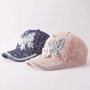 Detalle de gorras de béisbol de encaje con mariposa de diamantes de imitación brillantes.