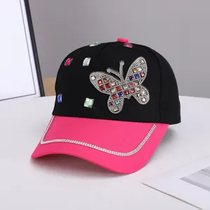 Primer plano detallado de la gorra con mariposa de diamantes, elegante diseño negro y rosa.