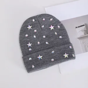 Detalle de gorro de punto gris con diamantes de imitación brillantes y estrellas de invierno.