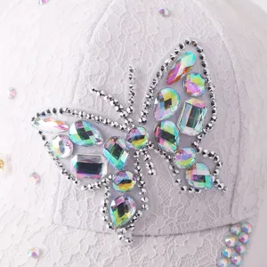 Primer plano detallado de una gorra de encaje blanco con brillante mariposa de estrás iridiscente.