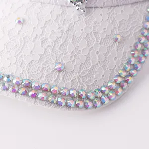 Vista detallada de gorra de béisbol de encaje blanco con diamantes de imitación iridiscentes.