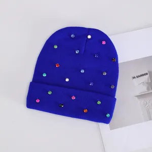 Primer plano detalle del gorro de punto azul real decorado con pedrería de colores.