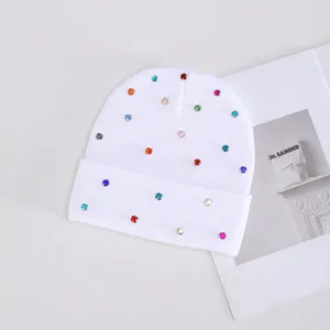 Primer plano detallado de un gorro de punto blanco decorado con diamantes de imitación.