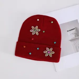 Detalle de primer plano de gorro de punto rojo oscuro con flor de pedrería y cristales brillantes.