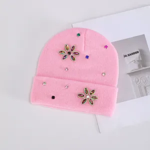 Primer plano de un gorro de invierno rosa para mujer con decoraciones de flores de estrass.