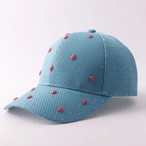 Nahaufnahme der hellblauen Netz-Baseballkappe, verziert mit Strasssteinen und Erdbeer-Charms.