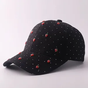 Schwarze Baseballkappe mit Strasspunkten und Erdbeer-Anhängern, stilvolles Sonnenschutz-Detail.