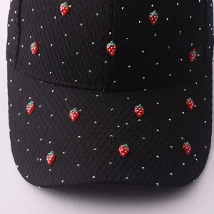 Nahaufnahme einer schwarzen Mesh-Baseballcap mit silbernen Strasssteinen und roten Erdbeeren.