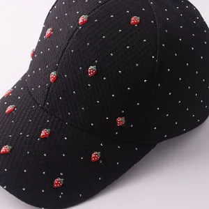 Detailaufnahme der schwarzen schwarzen Baseballkappe mit glänzenden Strasssteinen und Erdbeeren.