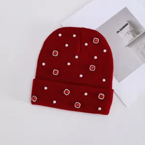 Vista detallada del gorro de punto de invierno rojo decorado con perlas y pedrería de estrás rojo.