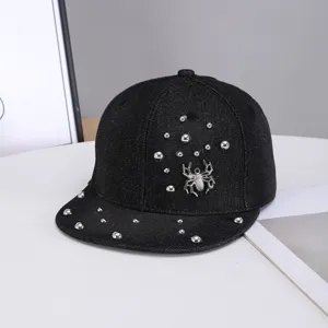 Primer plano de la gorra plana de mezclilla negra con remaches de metal y adorno de araña.