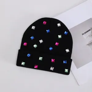 Vista detallada de gorro de punto negro decorado con brillantes cuadrados multicolores.
