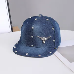 Vista detallada de gorra de béisbol de mezclilla con tachuelas metálicas y parche de toro.