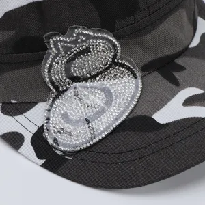 Gros plan detail de la casquette plate camouflage elegante avec ecusson strass argent.