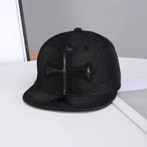 Primer plano de gorra plana de mezclilla negra con parche de cruz de cuero distintivo.