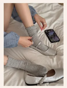 Gros plan sur les chaussettes mi-hautes grises à volants, tissu doux et fin printemps été.