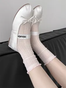 Weiße Satin-Ballerinas und rosa Spitzen-Netz-Mittelsocken, zarte Rüschenbündchen-Detailansicht.