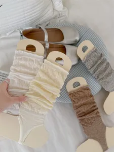 Close-up detail shot of knitted stirrup leg warmers in various soft colors on display.