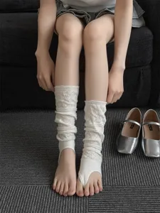 Detail shot of white hollow mesh stirrup leg warmers, ballet style slouch socks for women.