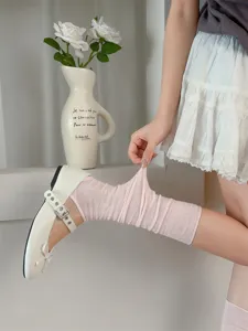 Detailed close-up of pink ballet-style stirrup leg warmers styled with white shoes.