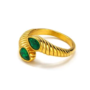 Macro detail of 18k gold plated ribbed snake ring featuring two pear-cut emerald green stones
