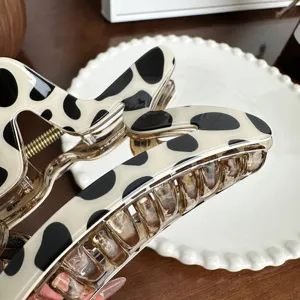 Large cow print hair claw clip with cream and black spots for elegant styling